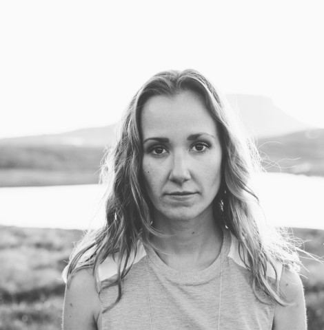 A black and white photo of a woman against a lake backdrop.